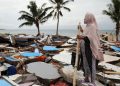 Seorang perempuan melihat desanya di Indonesia yang hancur akibat tsunami. (Foto: ©️ OCHA/Anthony Burke)