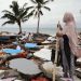 Seorang perempuan melihat desanya di Indonesia yang hancur akibat tsunami. (Foto: ©️ OCHA/Anthony Burke)